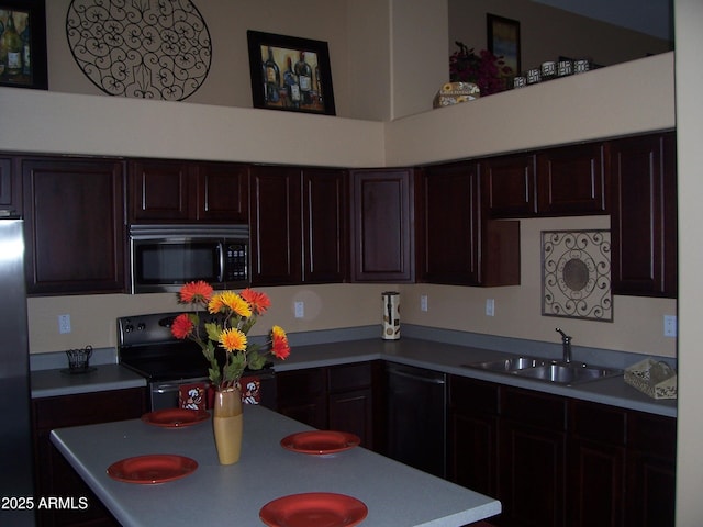 kitchen featuring black appliances, dark brown cabinets, a sink, and light countertops