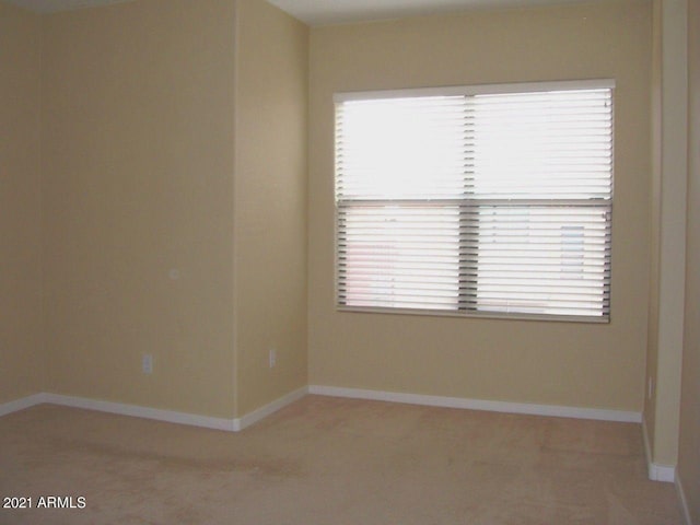 spare room with light colored carpet and baseboards