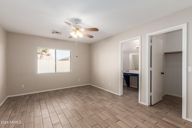 unfurnished bedroom with ceiling fan, a spacious closet, connected bathroom, light hardwood / wood-style floors, and a closet