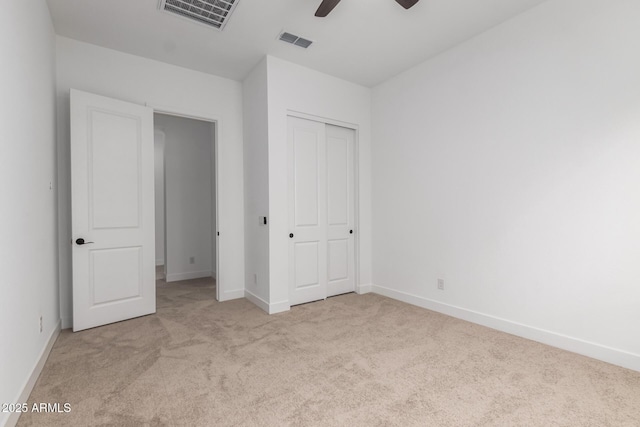 unfurnished bedroom featuring light carpet, a closet, and ceiling fan