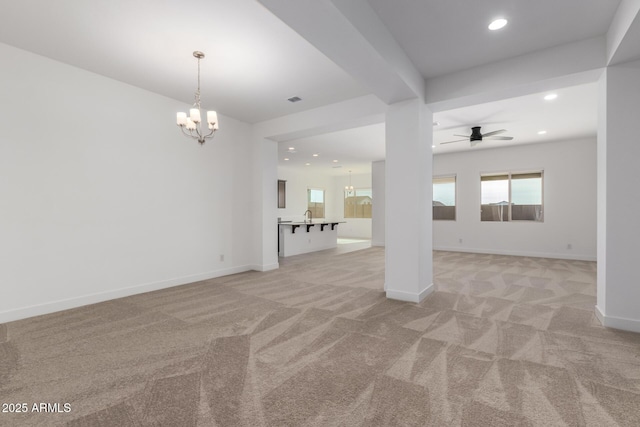 unfurnished living room with ceiling fan with notable chandelier and light colored carpet