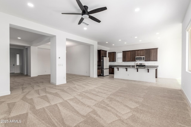 unfurnished living room with light carpet and ceiling fan