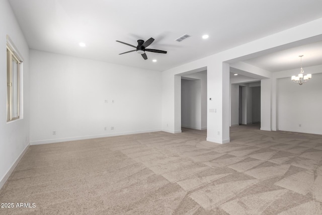 spare room featuring ceiling fan with notable chandelier and light colored carpet