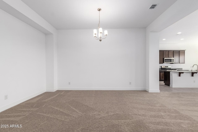 carpeted empty room with sink and a chandelier