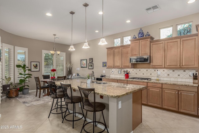 kitchen with decorative light fixtures, sink, a kitchen island with sink, a kitchen breakfast bar, and stainless steel appliances