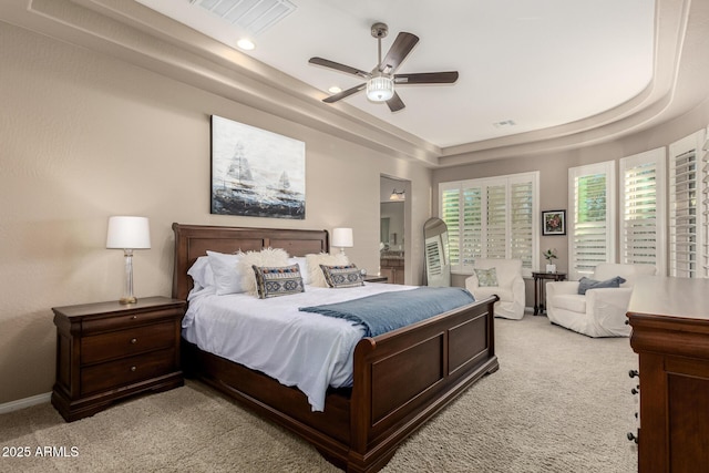 carpeted bedroom with ceiling fan and a tray ceiling