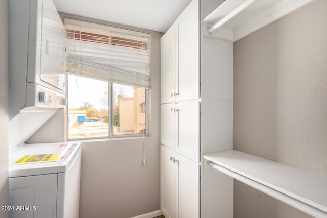 laundry area with cabinets and stacked washer / drying machine