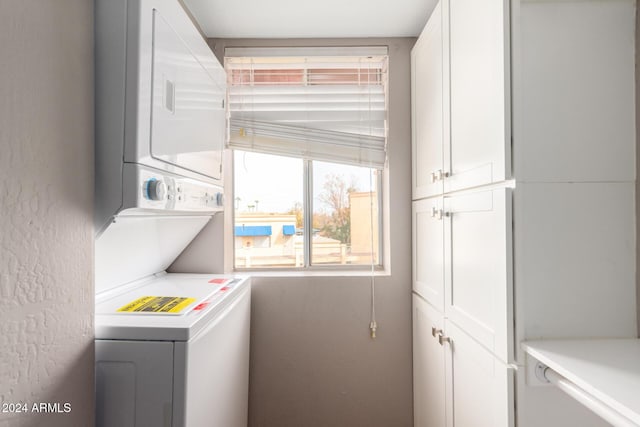 washroom with cabinets and stacked washer / dryer