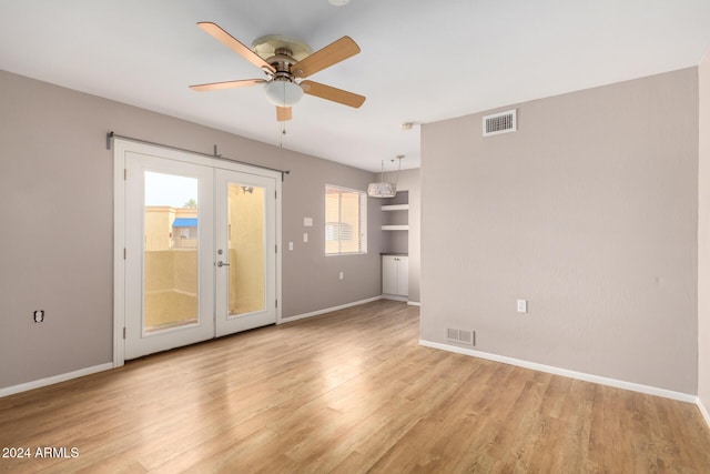 unfurnished room with light hardwood / wood-style floors, ceiling fan, built in shelves, and french doors