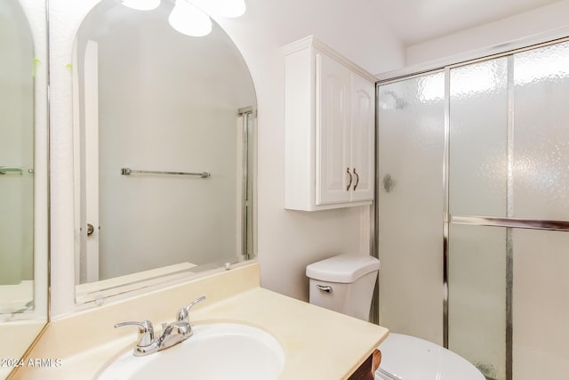 bathroom with a shower with door, vanity, and toilet