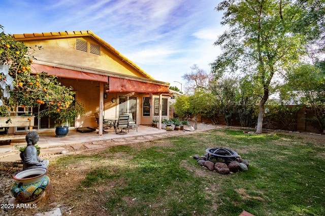 back of house featuring a fire pit, a patio area, and a lawn