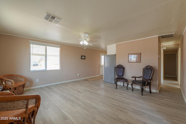 sitting room featuring crown molding, ceiling fan, and light wood-type flooring