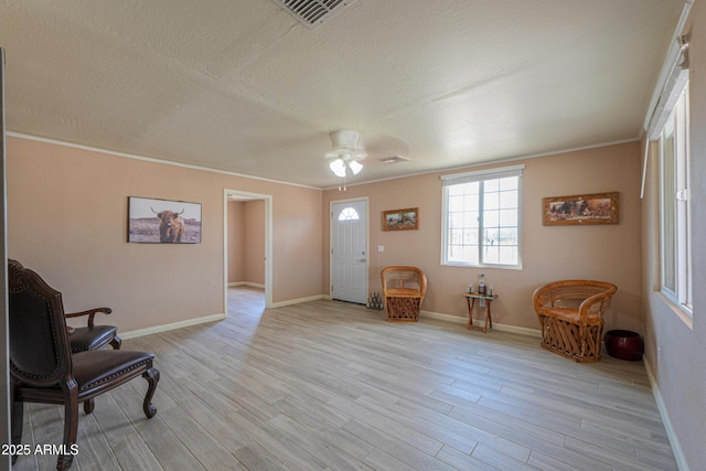 sitting room featuring ceiling fan, crown molding, light hardwood / wood-style flooring, and a textured ceiling