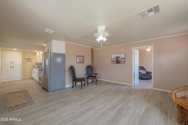 living area with crown molding, ceiling fan, and light hardwood / wood-style floors