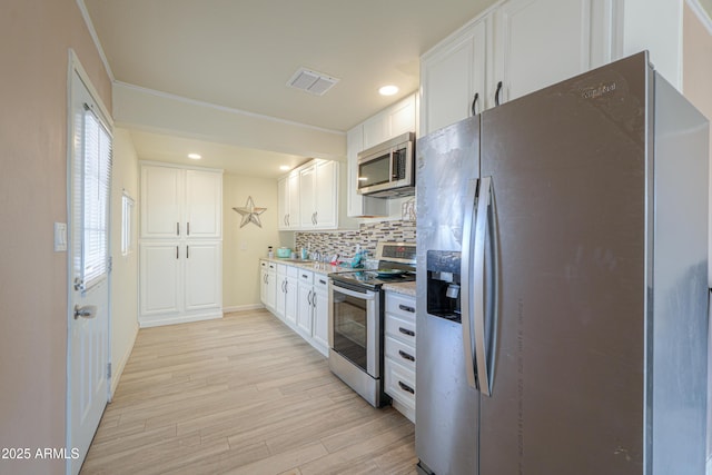 kitchen with stainless steel appliances, white cabinetry, tasteful backsplash, and light hardwood / wood-style floors