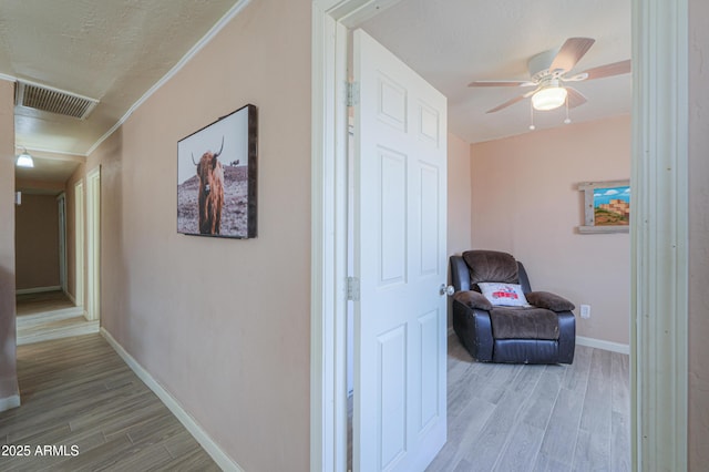 hall featuring ornamental molding, a textured ceiling, and light hardwood / wood-style floors