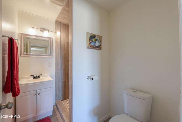 bathroom featuring vanity, a tile shower, crown molding, and toilet