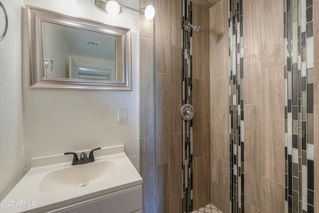 bathroom with vanity and a tile shower