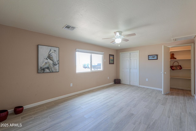 unfurnished bedroom with ceiling fan, a closet, light hardwood / wood-style floors, and a textured ceiling