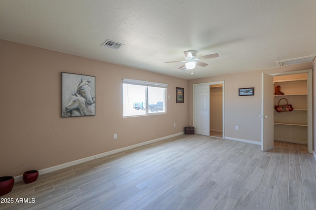 unfurnished bedroom with ceiling fan, a textured ceiling, and light wood-type flooring