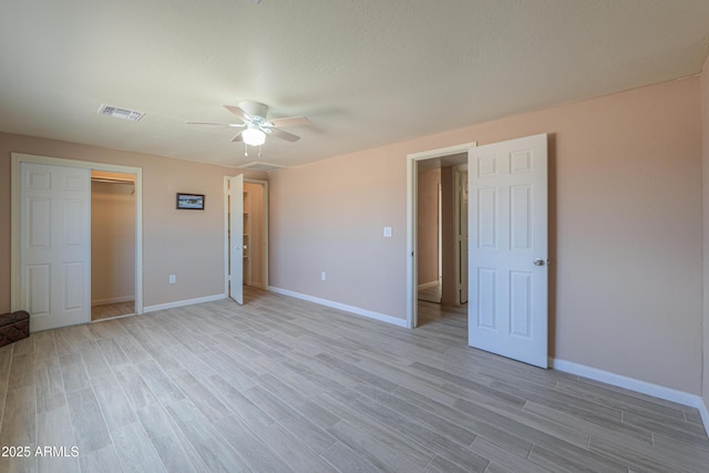 unfurnished bedroom featuring ceiling fan, light hardwood / wood-style floors, and a closet