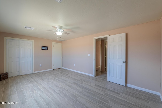 unfurnished bedroom with ceiling fan, a textured ceiling, light wood-type flooring, and a closet