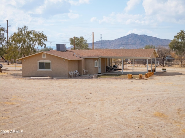 back of property featuring a mountain view and central AC