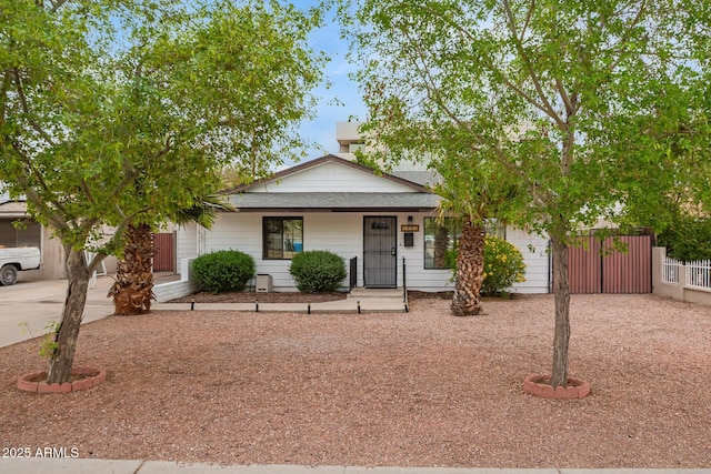 view of front of house featuring an attached garage, a porch, roof with shingles, concrete driveway, and fence