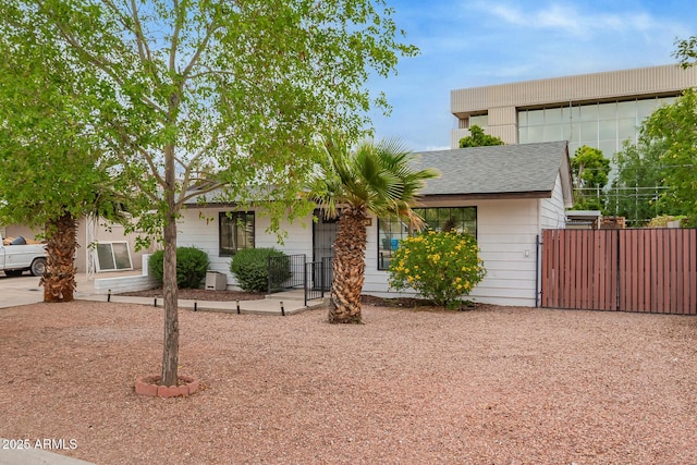 single story home featuring roof with shingles and fence