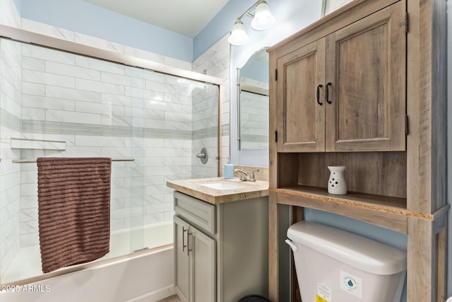 bathroom featuring combined bath / shower with glass door, vanity, and toilet