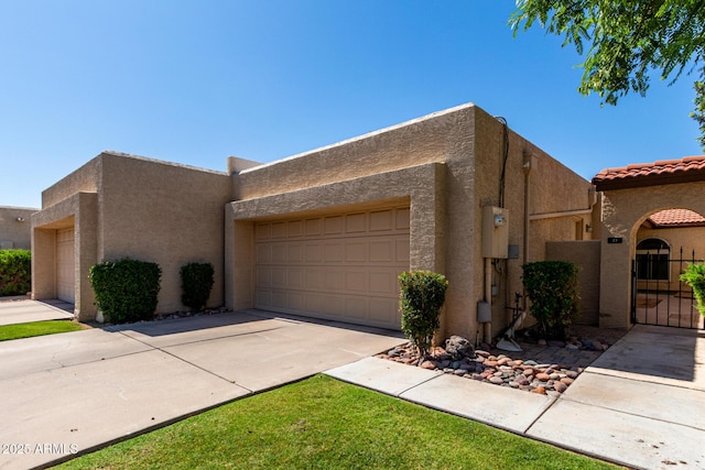 2059 E Brown Rd Unit 35, Mesa, AZ 85213 - view of front of home featuring an attached garage, stucco siding, driveway, a gate, and a tiled roof
