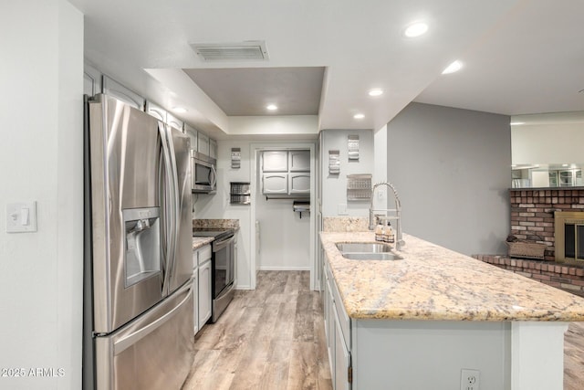 2059 E Brown Rd Unit 35, Mesa, AZ 85213 - kitchen featuring appliances with stainless steel finishes, a peninsula, light wood finished floors, light stone countertops, and a fireplace