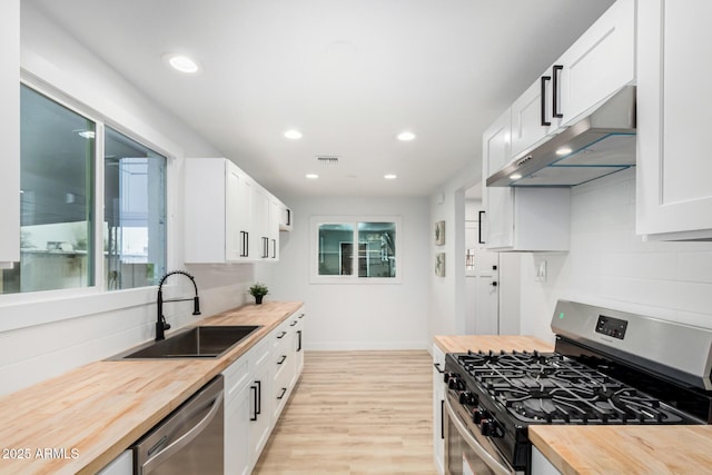 kitchen featuring visible vents, butcher block countertops, appliances with stainless steel finishes, under cabinet range hood, and a sink