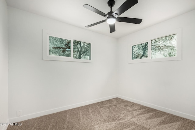 carpeted empty room featuring ceiling fan and baseboards