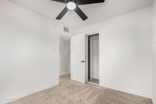 unfurnished bedroom with a closet, visible vents, light carpet, ceiling fan, and baseboards