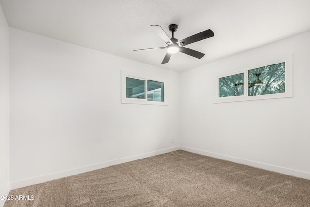 carpeted spare room with ceiling fan and baseboards
