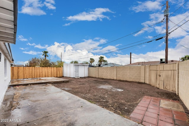 view of yard with an outbuilding, a patio area, a fenced backyard, and a storage unit