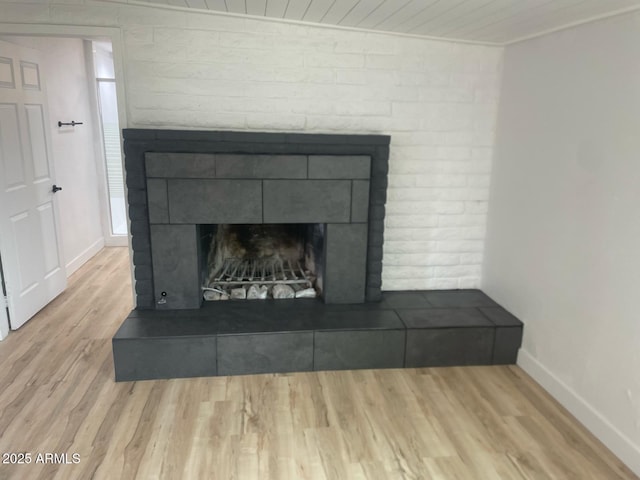 interior details featuring a fireplace with raised hearth, baseboards, and wood finished floors