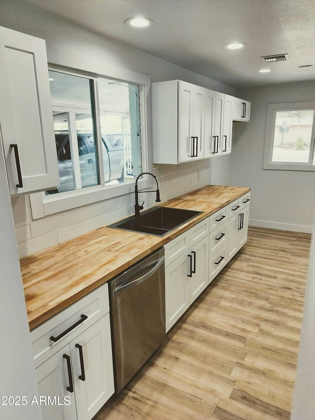 kitchen featuring light wood finished floors, visible vents, butcher block countertops, stainless steel dishwasher, and a sink
