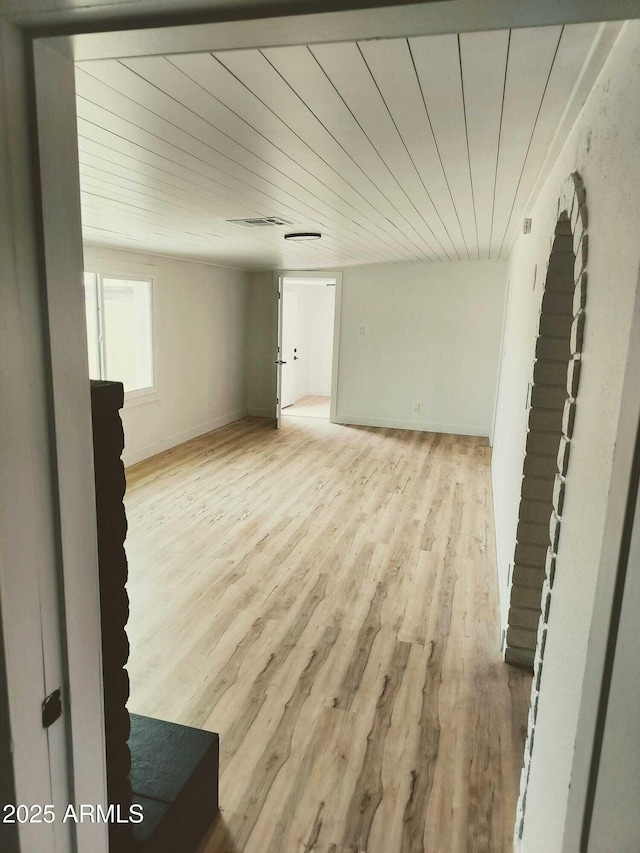 unfurnished room with visible vents, wood ceiling, light wood-style flooring, and baseboards