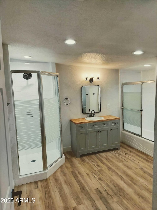 bathroom with recessed lighting, a shower with shower door, vanity, a textured ceiling, and wood finished floors