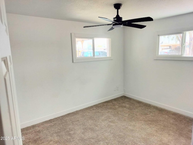 empty room featuring a textured ceiling, carpet floors, a ceiling fan, and baseboards