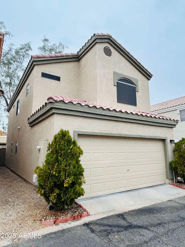 view of front of house featuring a garage, a tiled roof, and stucco siding