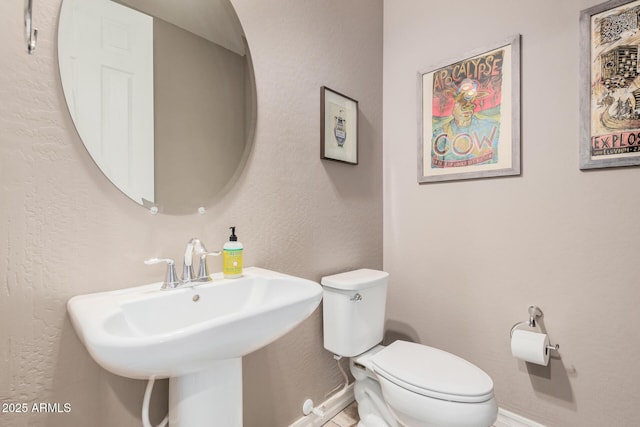 bathroom with toilet, baseboards, and a sink