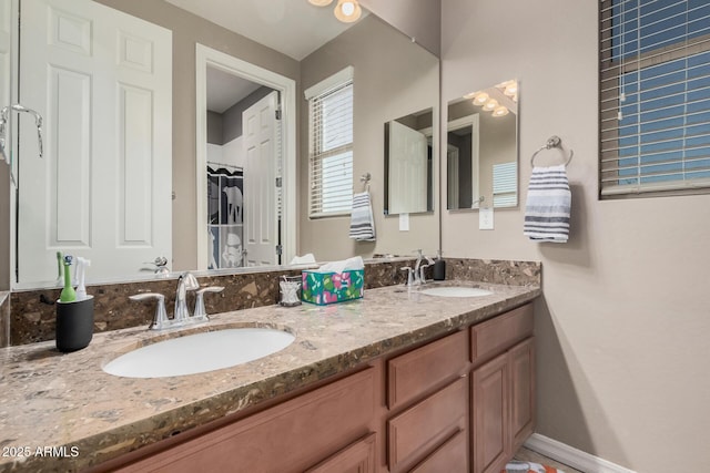 bathroom with double vanity, baseboards, and a sink