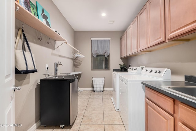 clothes washing area with cabinet space, light tile patterned flooring, a sink, independent washer and dryer, and baseboards