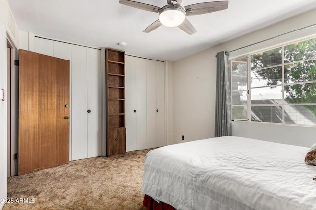 bedroom featuring two closets, carpet, and a ceiling fan