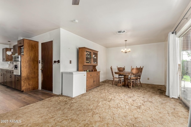 dining space featuring a chandelier and light carpet