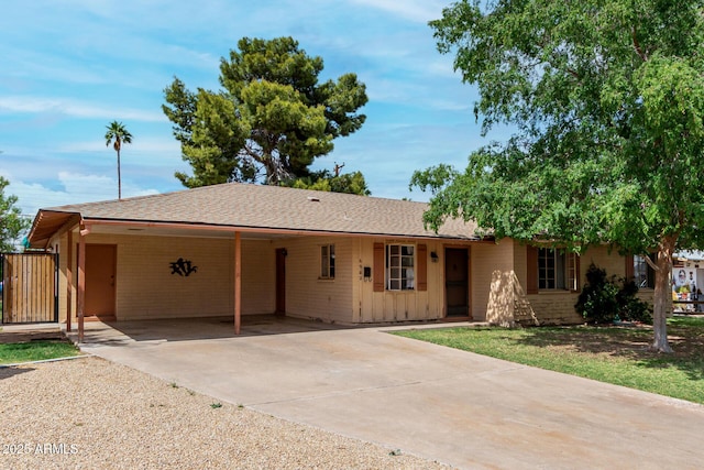 ranch-style home featuring an attached carport, driveway, and roof with shingles