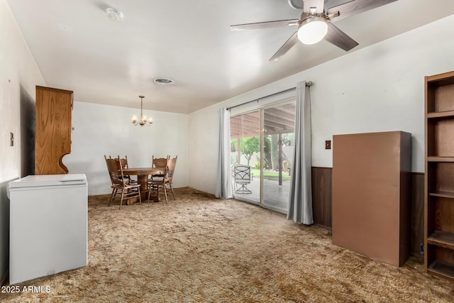 dining area with a chandelier, carpet floors, a ceiling fan, and wainscoting